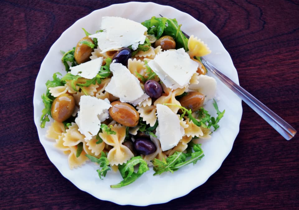 Pasta salad with olives, arugula, and shaved cheese
