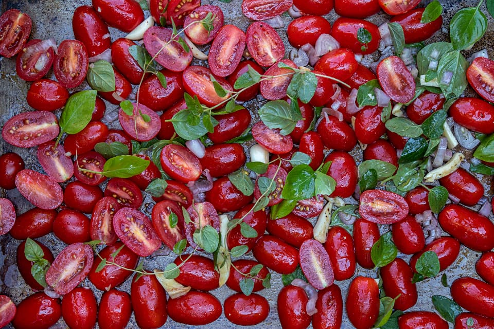 Vine-ripened tomatoes roasting with fresh basil